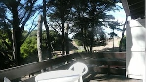An outdoor seating area with a table and chairs, surrounded by trees and a view of a road. - Apart E Luru (Mar de Las Pampas)