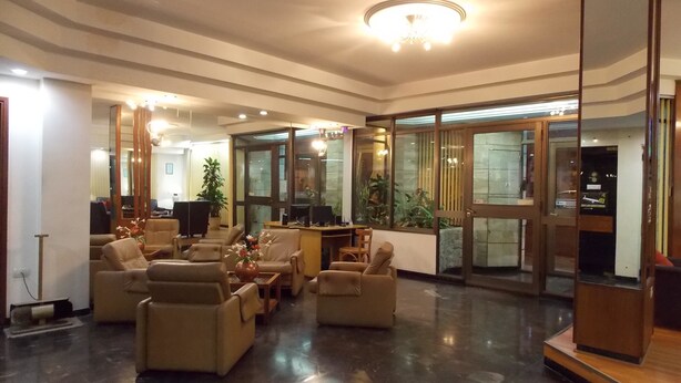 Eine geräumige Lobby mit Ledersofas, einem Empfangstresen und einem großen Spiegel.