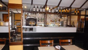 Ein Restaurant mit Barbereich, Holzkästen und -tischen, gedeckt mit weißen Tischdecken.