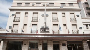 Ein mehrgeschossiges Gebäude mit einem auffälligen "VIENA"-Schild, das eine symmetrische Fassade mit gleichmäßig angeordneten Fenstern und Balkonen zeigt.