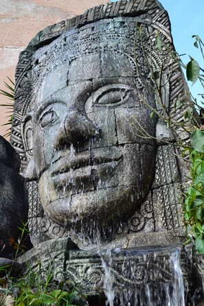 A stone sculpture with intricate carvings and a water feature. - Mon Petit Hotel (Villa Carlos Paz)