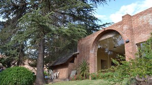 Un bâtiment en briques doté d’une grande entrée en arc de cercle, entouré de verdure et d’arbres.