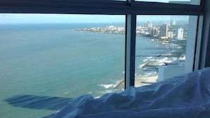 Quarto de hotel em um edifício alto, com vista para a costa e o horizonte da cidade.