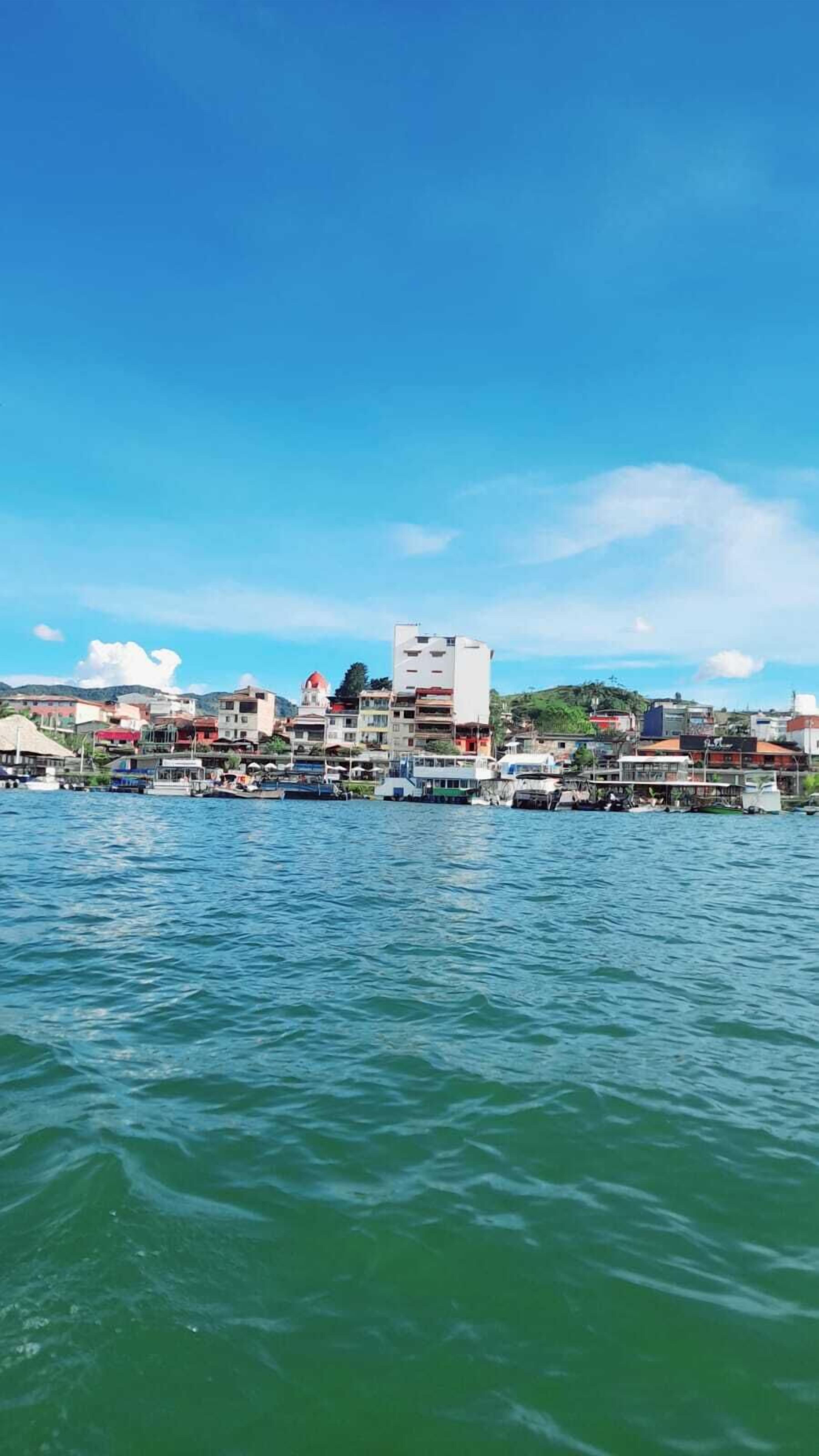 Une ville côtière avec des bâtiments le long du front de mer, des bateaux amarrés et un ciel bleu dégagé.