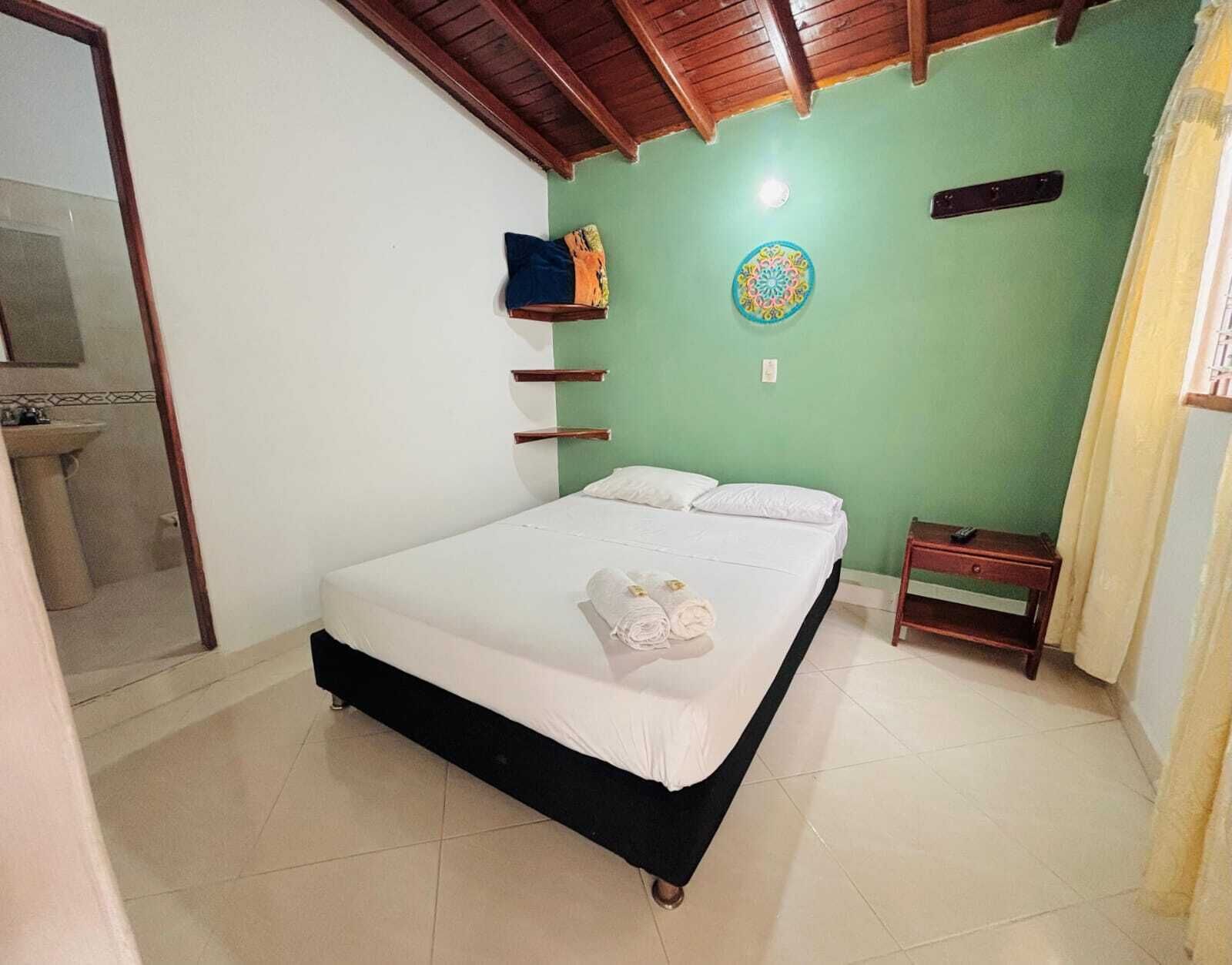 A single bed with a black frame, white bedding, and a small bedside table with a lamp.
