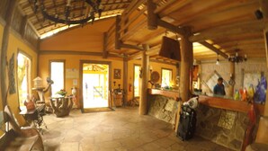 A spacious lobby with a stone floor, wooden beams, and a reception desk.