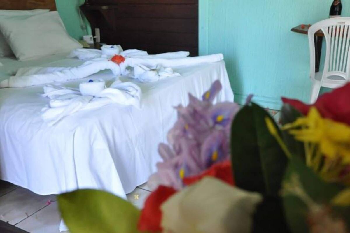 A hotel room with a bed, a table with folded towels, and a chair.