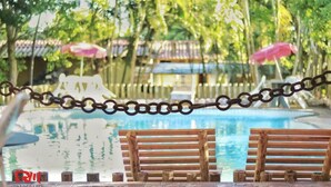 A pool area with wooden benches and a chain barrier.