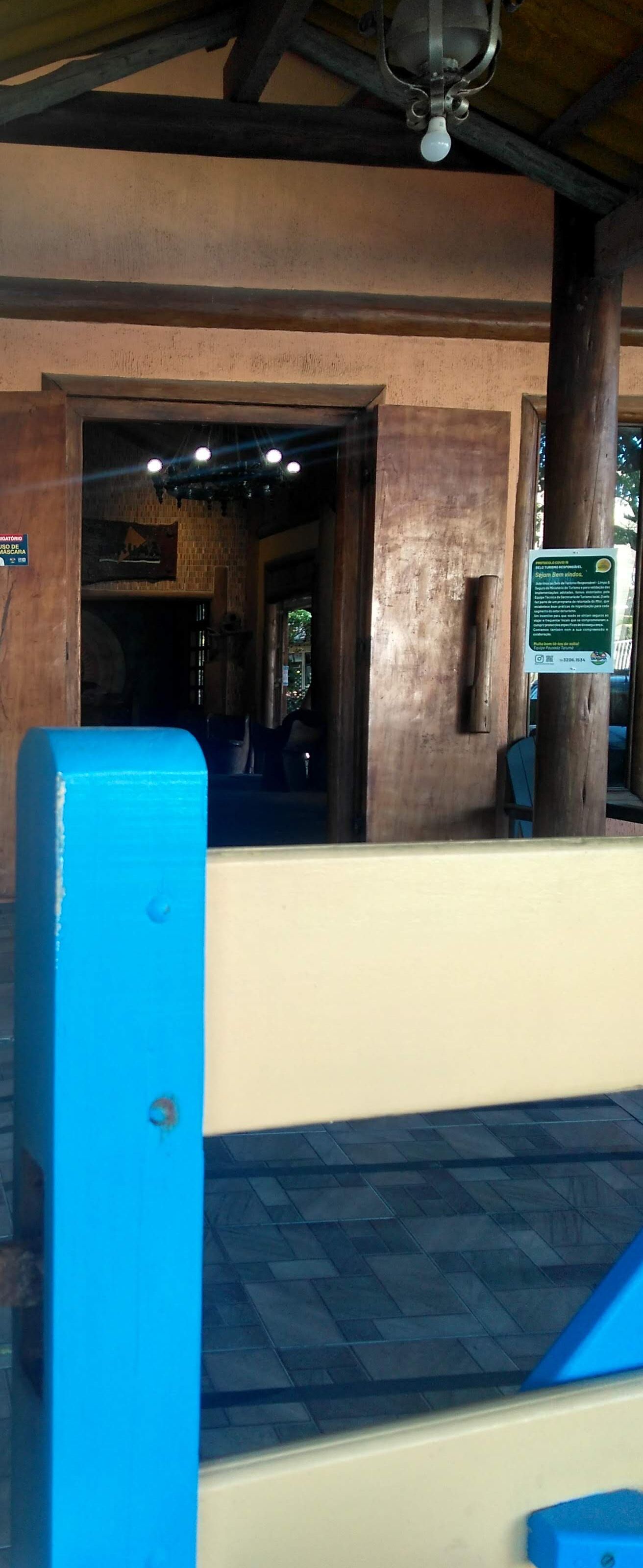 A building entrance with a blue bench, a wooden pillar, and a ceiling fan.