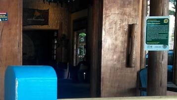 A building entrance with a blue bench, a wooden pillar, and a ceiling fan.