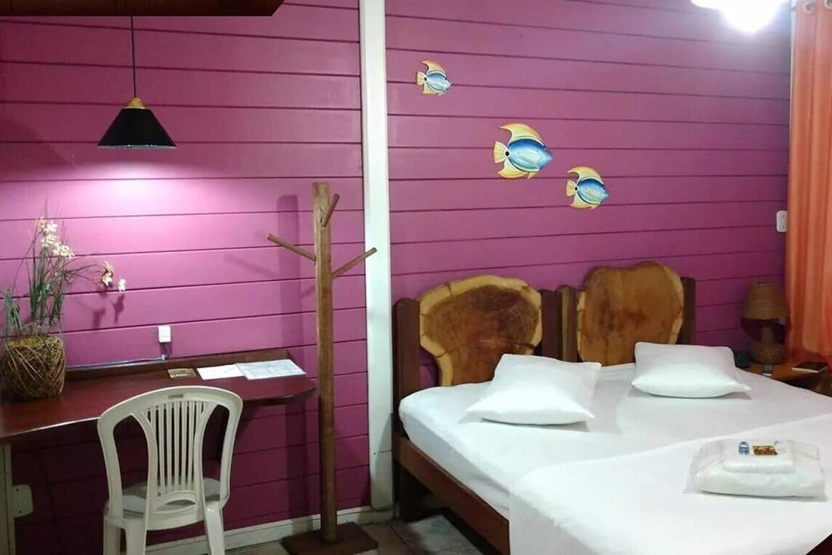 A room with a bed, a desk, a chair, a plant, and a wall with fish decals.