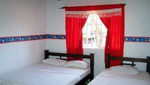 A room with two single beds, red curtains, and a window with a view of the street. - Finca 028 (Restrepo)