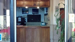 A kitchen with wooden cabinets, a countertop, and a window with a grid pattern. - Gran Hotel America (Buenos Aires)