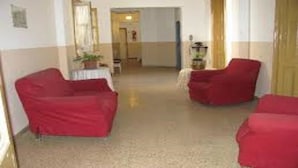 A hallway with two red armchairs and a small table with a plant. - Gran Hotel America (Buenos Aires)