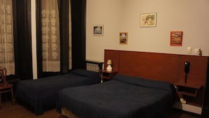 A hotel room with two single beds, a wooden headboard, a nightstand with a lamp, and a radiator. - Gran Hotel America (Buenos Aires)