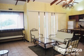 A living room with a glass-top table, two sofas, a bench, and a small round table.