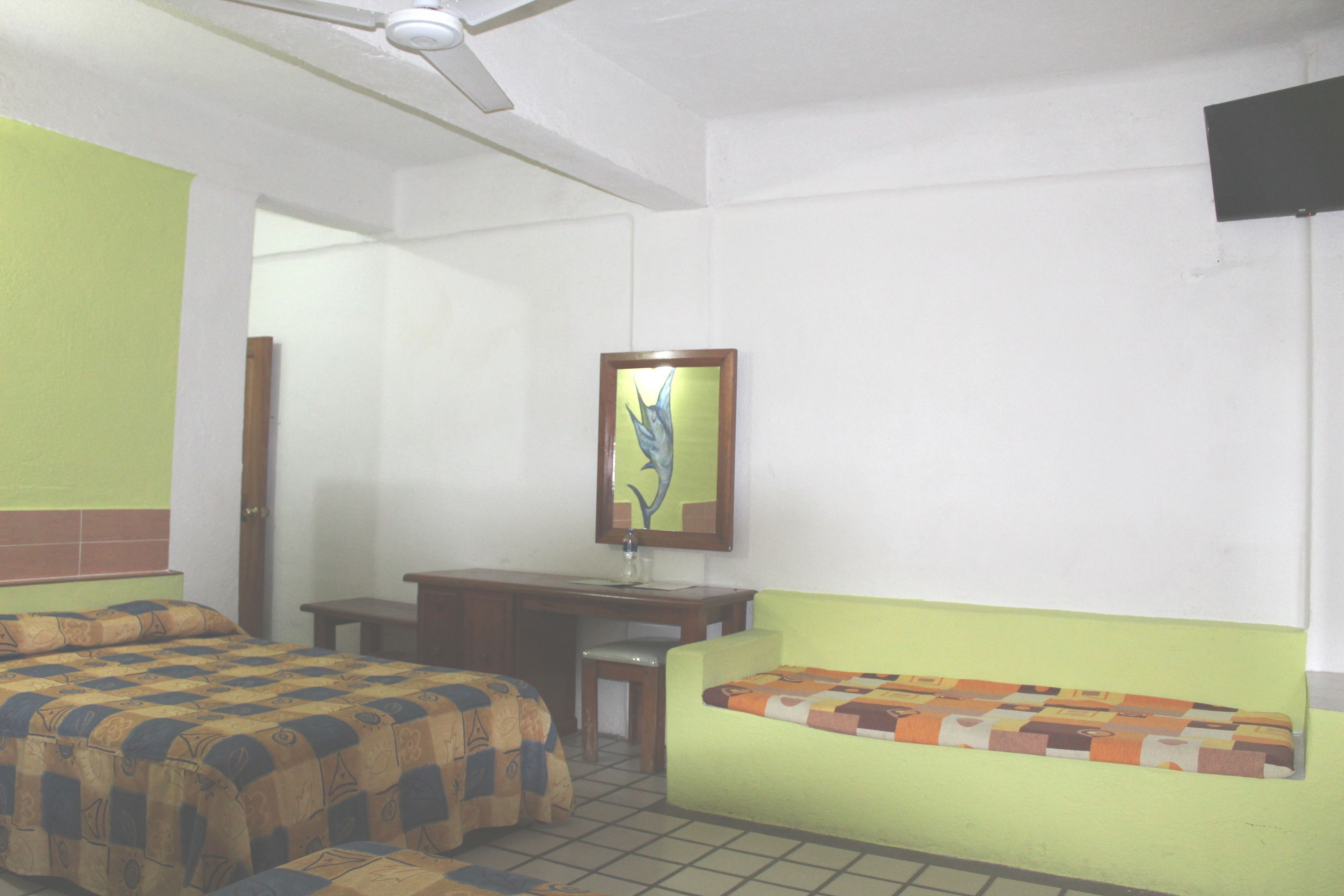A room with a bed, a desk, and a chair. There is a painting on the wall.
