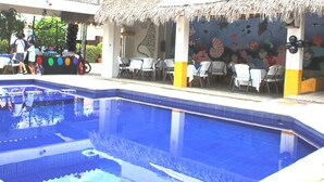 A swimming pool with a thatched roof seating area and a mural of marine life. - Hotel Arrecife Plus (Santa María Huatulco)