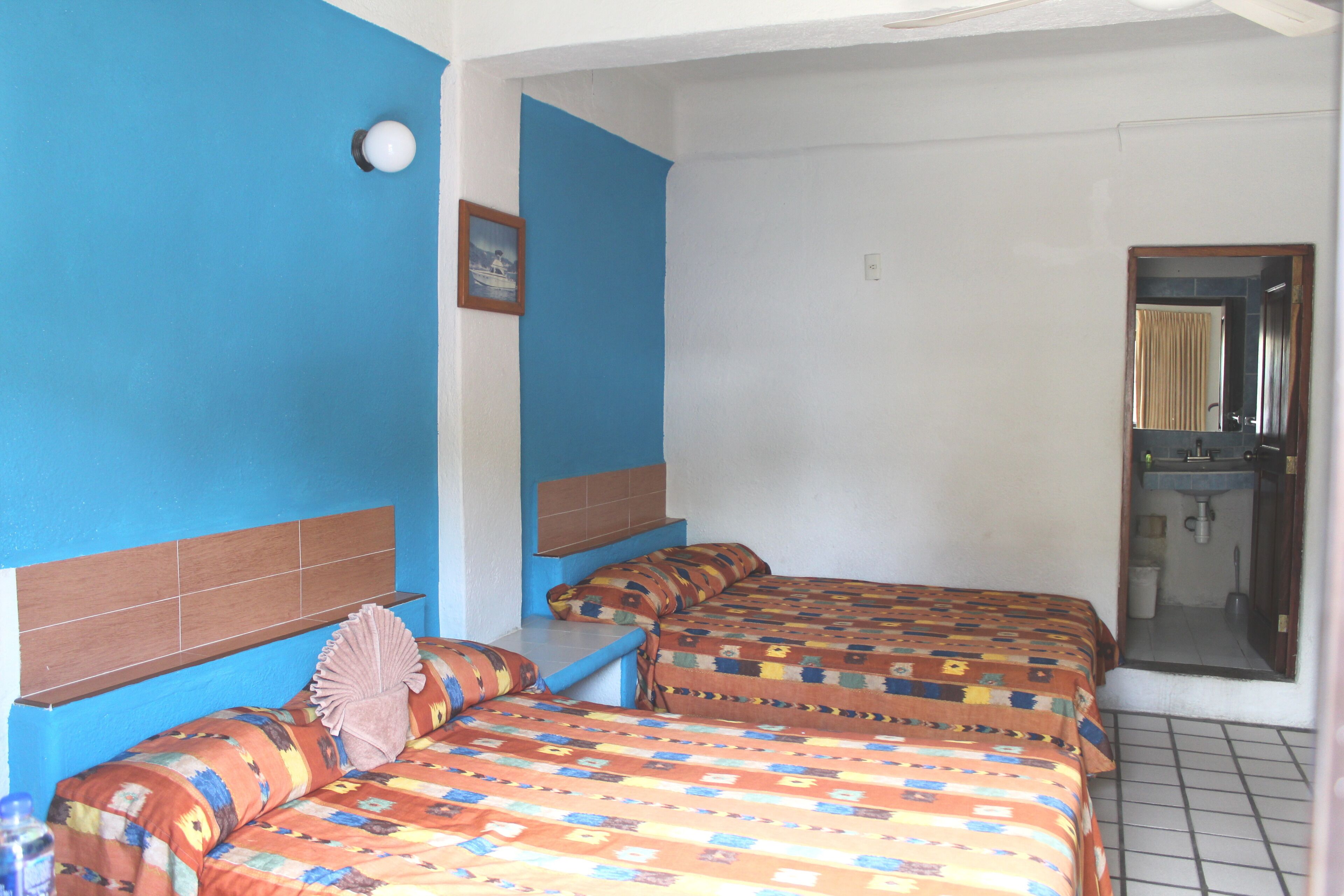 A room with two beds, a bathroom, and a small window.