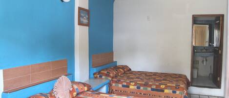 A room with two beds, a bathroom, and a small window.