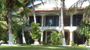 A building with a white facade, multiple windows, and a tiled roof. - Hotel Arrecife Plus (Santa María Huatulco)