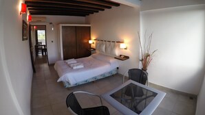 Een hotelkamer met een bed, nachtkastjes, een stoel, een tafeltje en een plant in een pot.