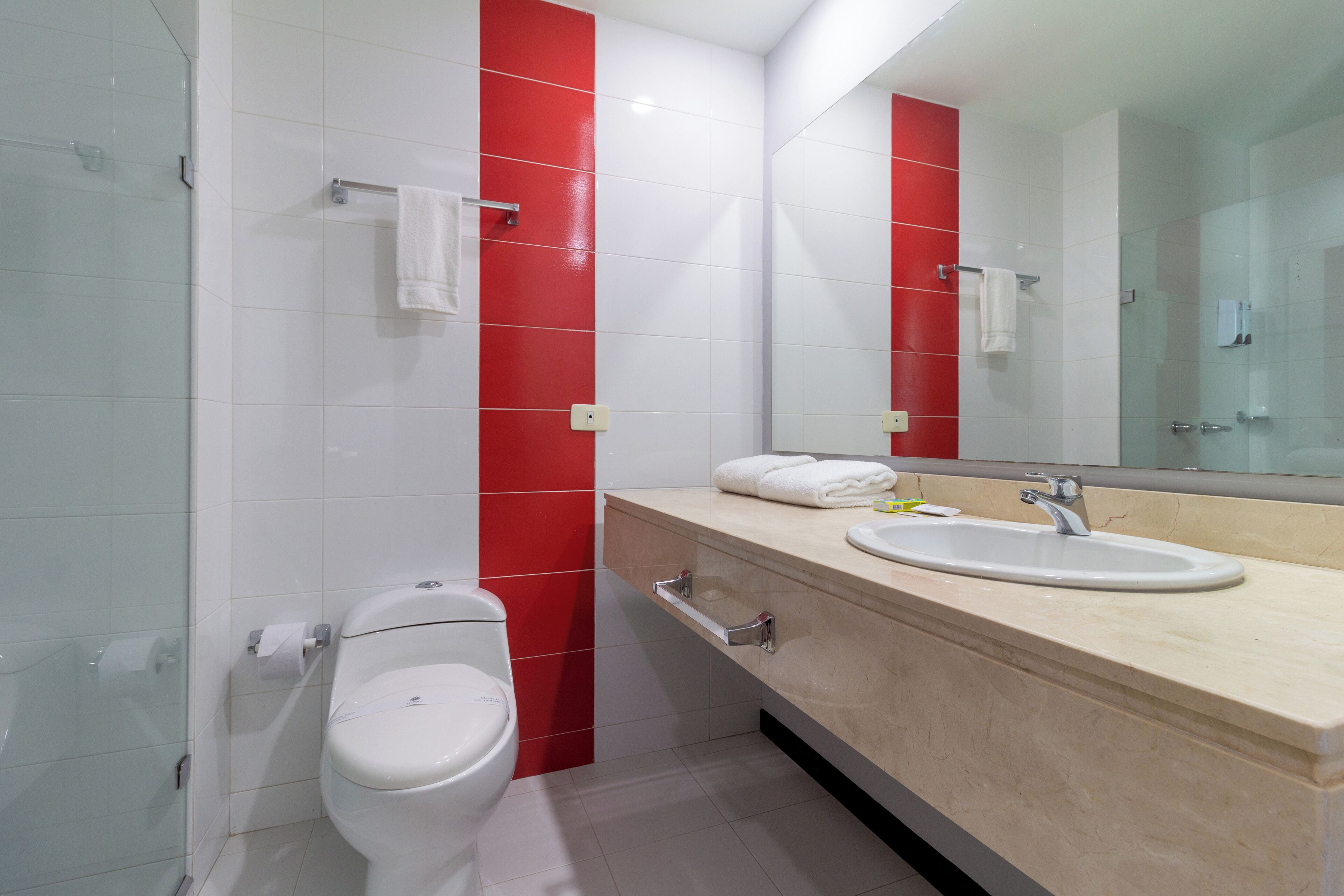 A modern bathroom with a toilet, sink, and glass shower enclosure.