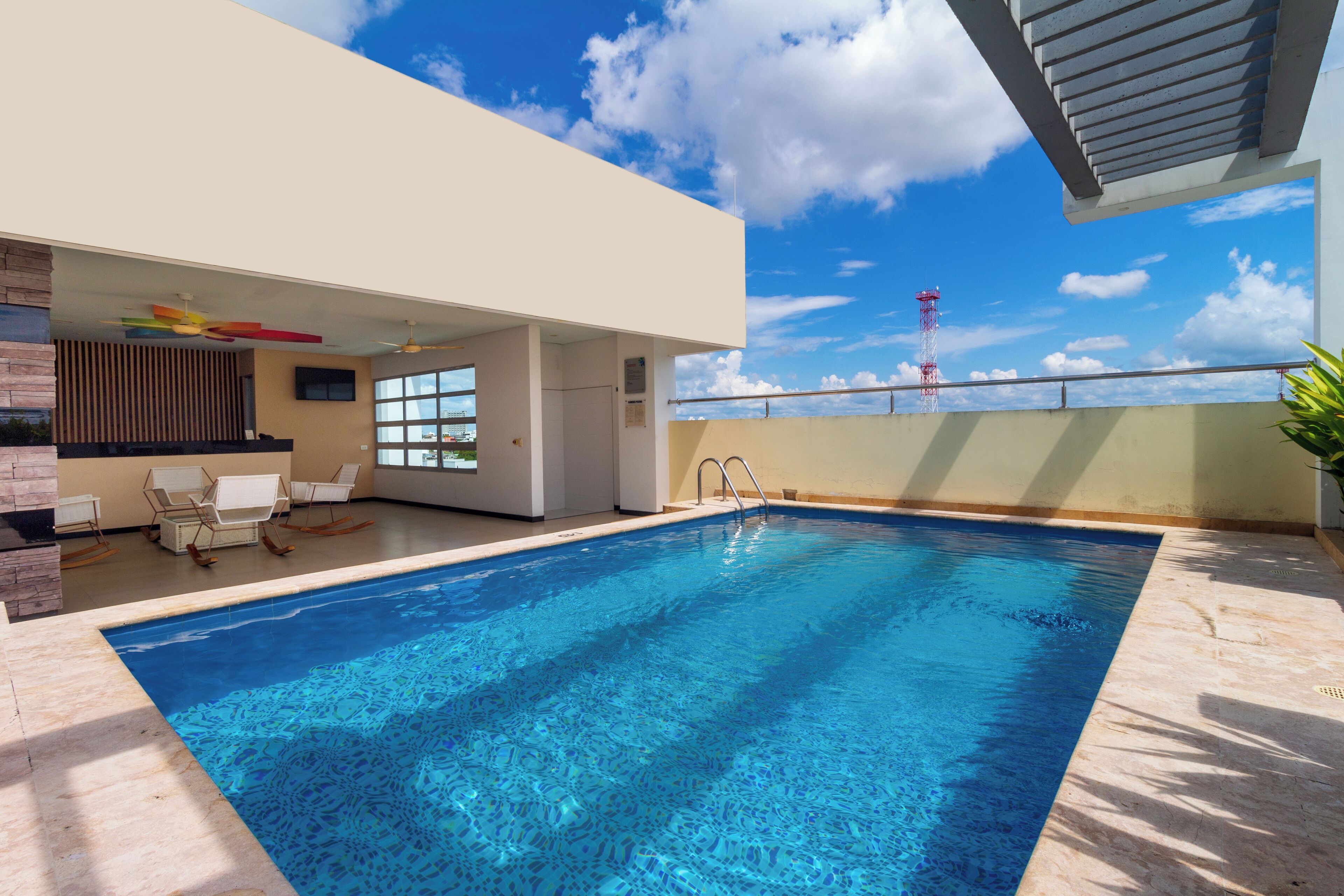 A modern indoor swimming pool with clear blue water, a sunroof, and a view of a tower in the background.