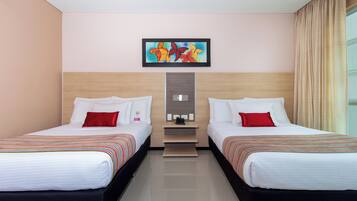 Habitación de hotel con dos camas, una mesita y un cuadro en la pared.