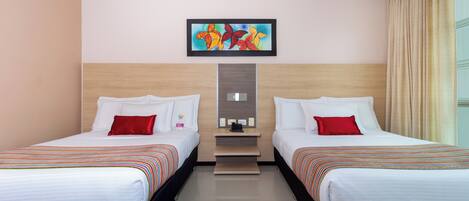 Habitación de hotel con dos camas, una mesita y un cuadro en la pared.