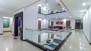 Un intérieur moderne à plusieurs niveaux, doté d’une balustrade en verre, d’un ventilateur de plafond et d’un escalier.