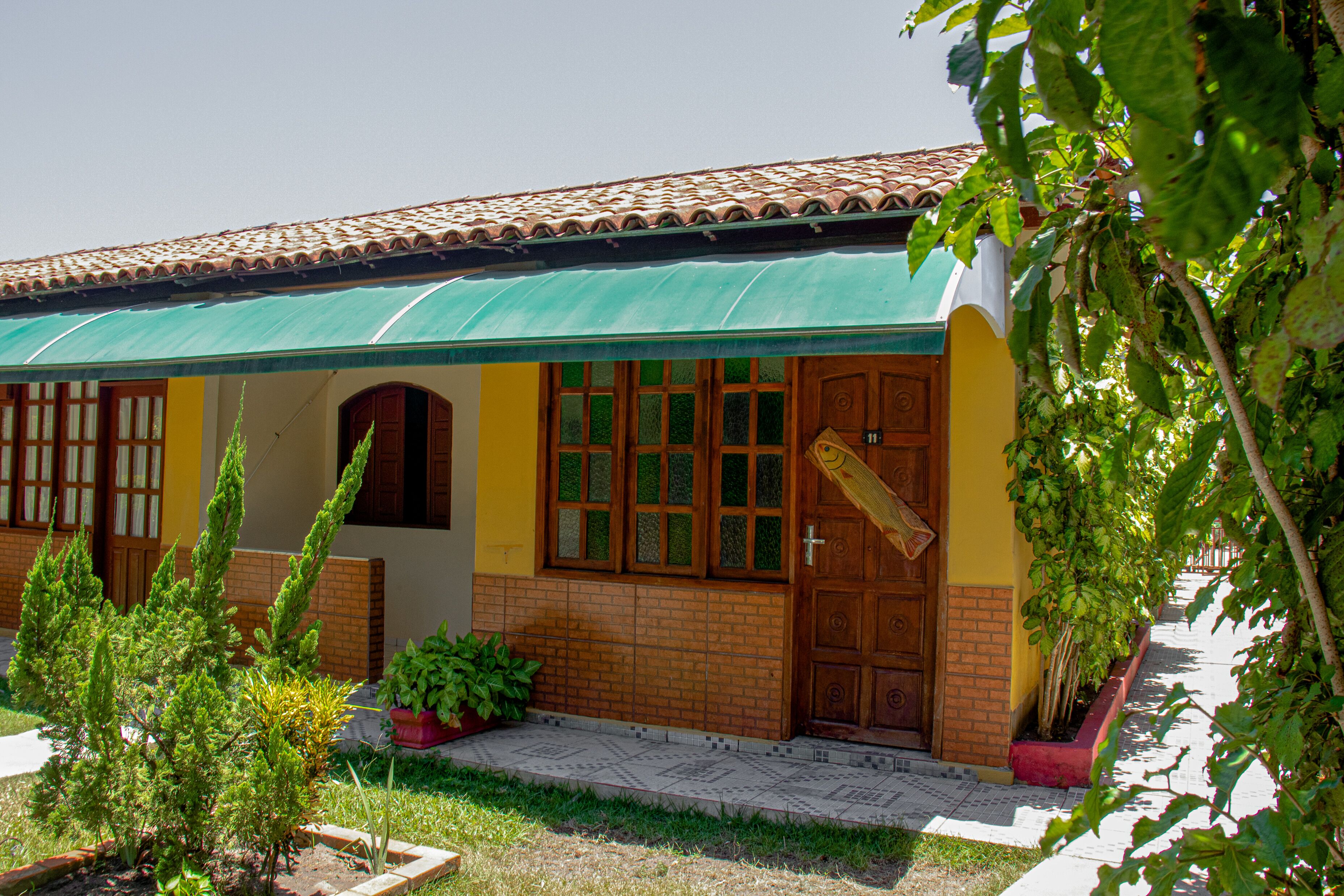 A house with a green awning, a brick facade, and a wooden door.
