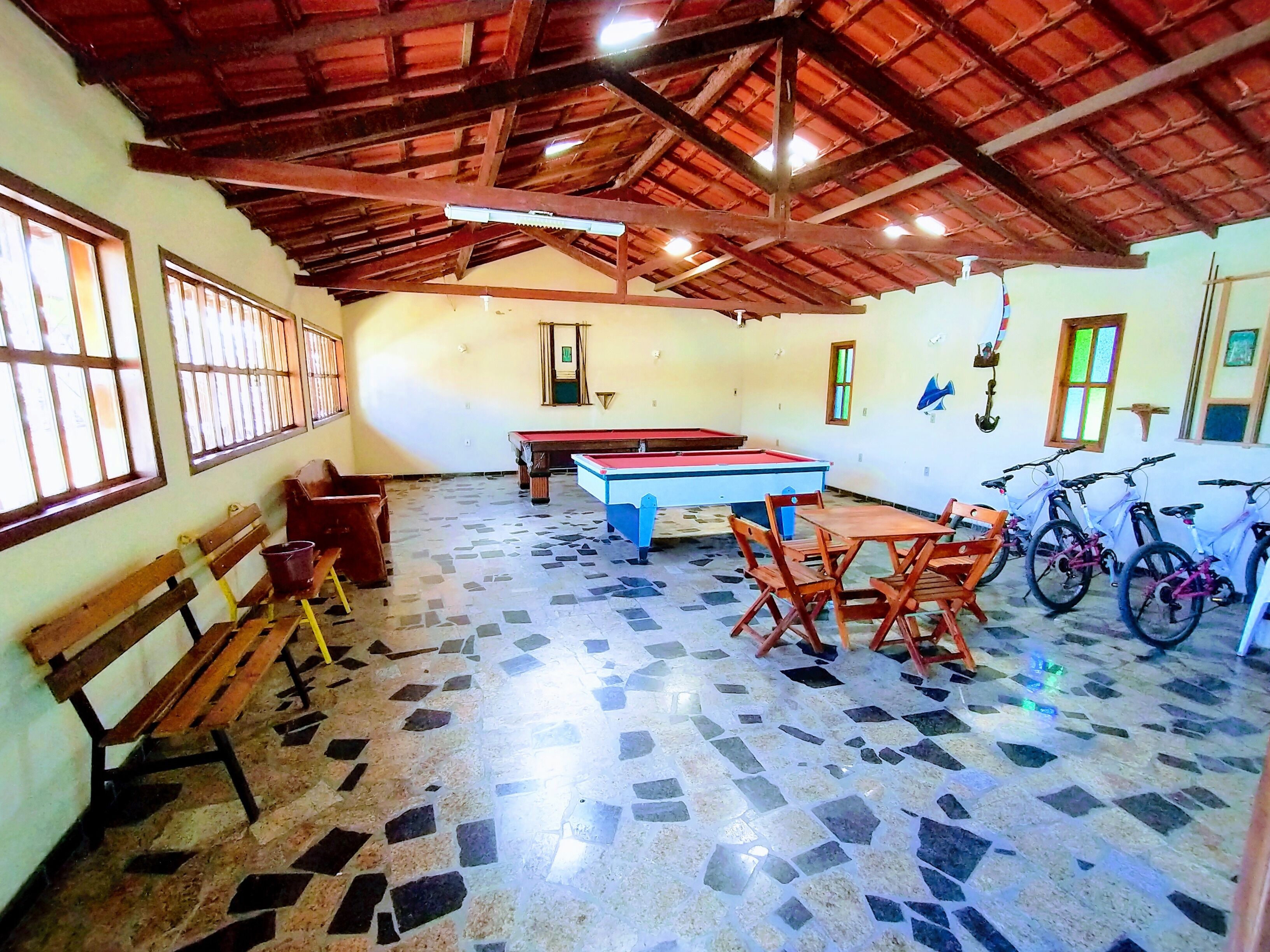 Una habitación con mesa de billar, sillas de madera, un banco y bicicletas.