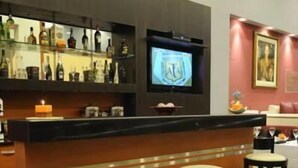 A bar area with a counter, stools, and a television screen. - Hotel Osam (Buenos Aires)