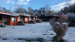 Un'area esterna innevata con un edificio dalla facciata rossa e fondamenta in pietra.