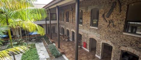 A courtyard with stone walls, a palm tree, and outdoor seating.