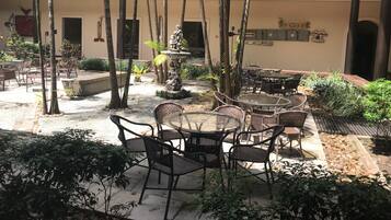 A courtyard with outdoor seating, a fountain, and a building with multiple floors and balconies.
