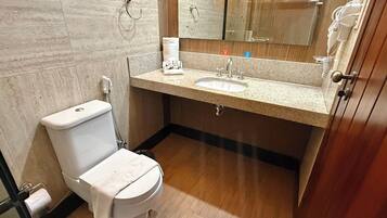 Un baño con inodoro, lavamanos, espejo y toallero.