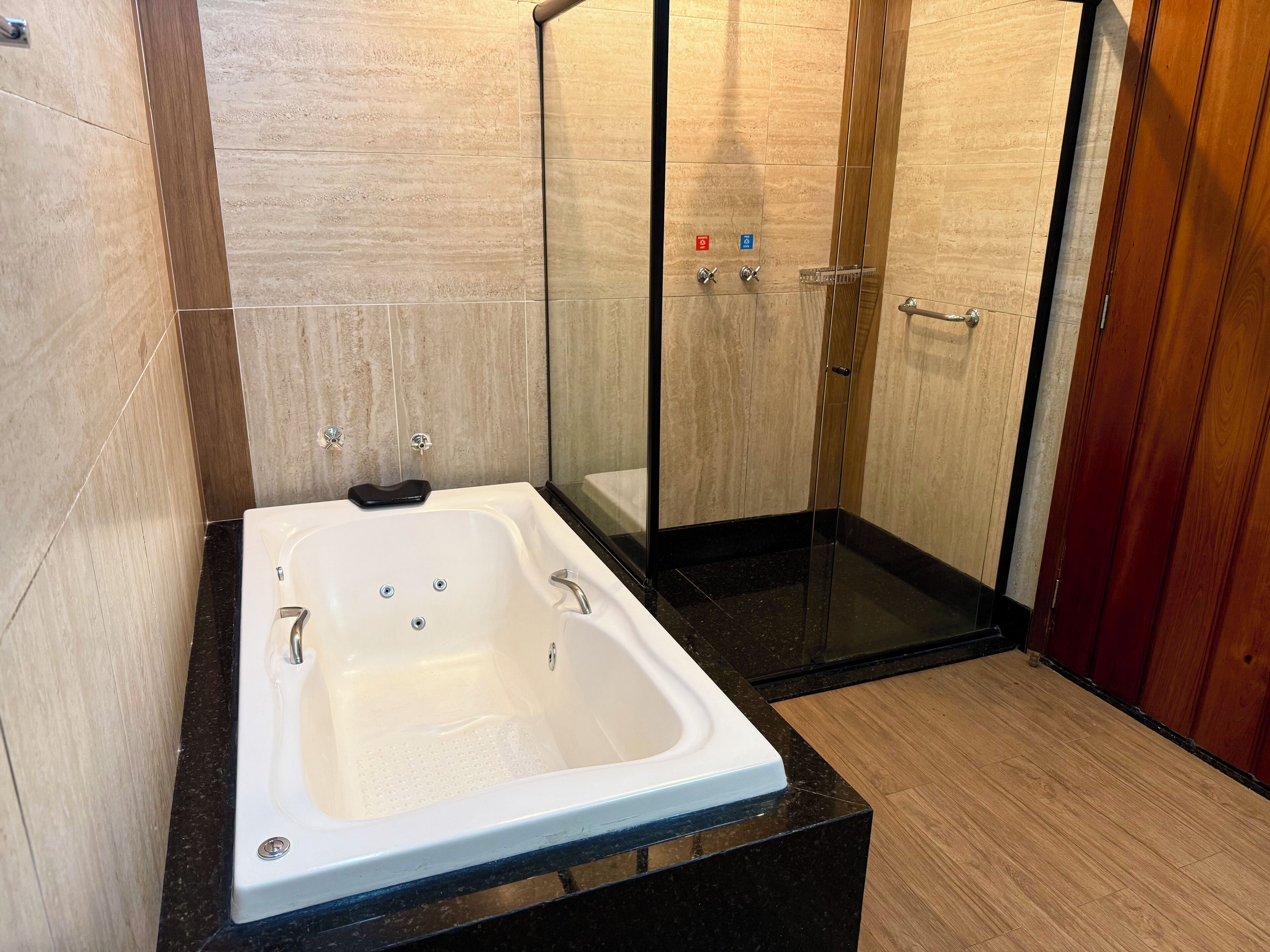 A modern bathroom with a freestanding bathtub, glass shower enclosure, and wooden flooring.