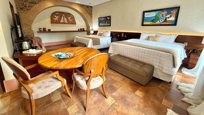 Ein Hotelzimmer mit einem Bett, einem Esstisch mit Stühlen, einer Kaffeemaschine und einem Kamin.