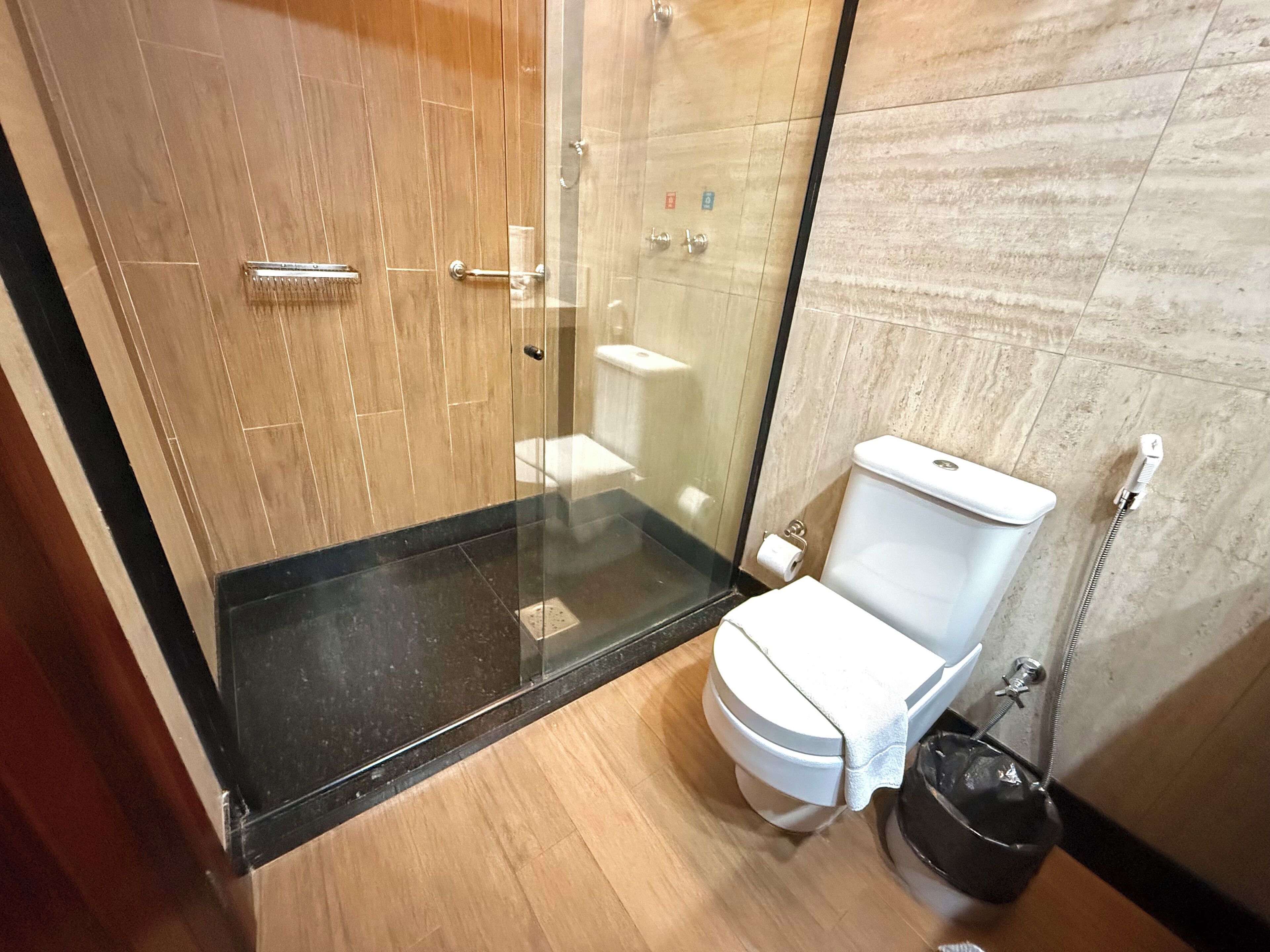 Un baño moderno con ducha envuelta en vidrio, inodoro blanco y suelo negro.