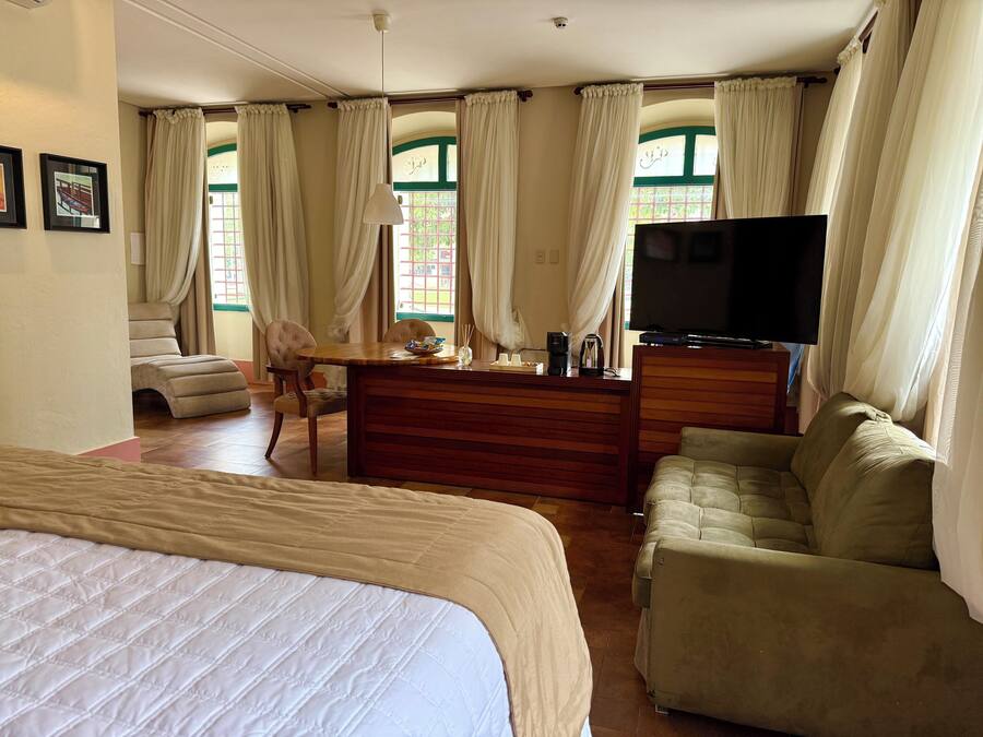Een hotelkamer met een bed, een slaapbank, een bureau met een televisie en gordijnen.