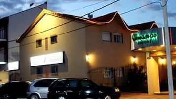 Un edificio con un letrero de neón que dice “Hotel” y un cartel que indica “Hotel de France”. Hay coches estacionados frente al edificio.