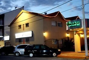 Un edificio con un letrero de neón que dice “Hotel” y un cartel que indica “Hotel de France”. Hay coches estacionados frente al edificio.