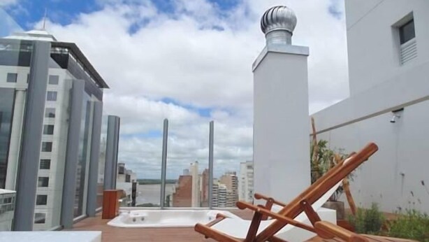 A rooftop terrace with a hot tub, lounge chairs, and a view of the cityscape. - Catamarca Suites Land (Rosario)