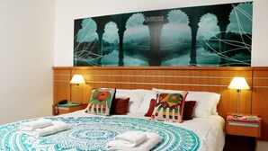 A hotel room with a large bed, two bedside lamps, a nightstand, and a wall painting. - Catamarca Suites Land (Rosario)