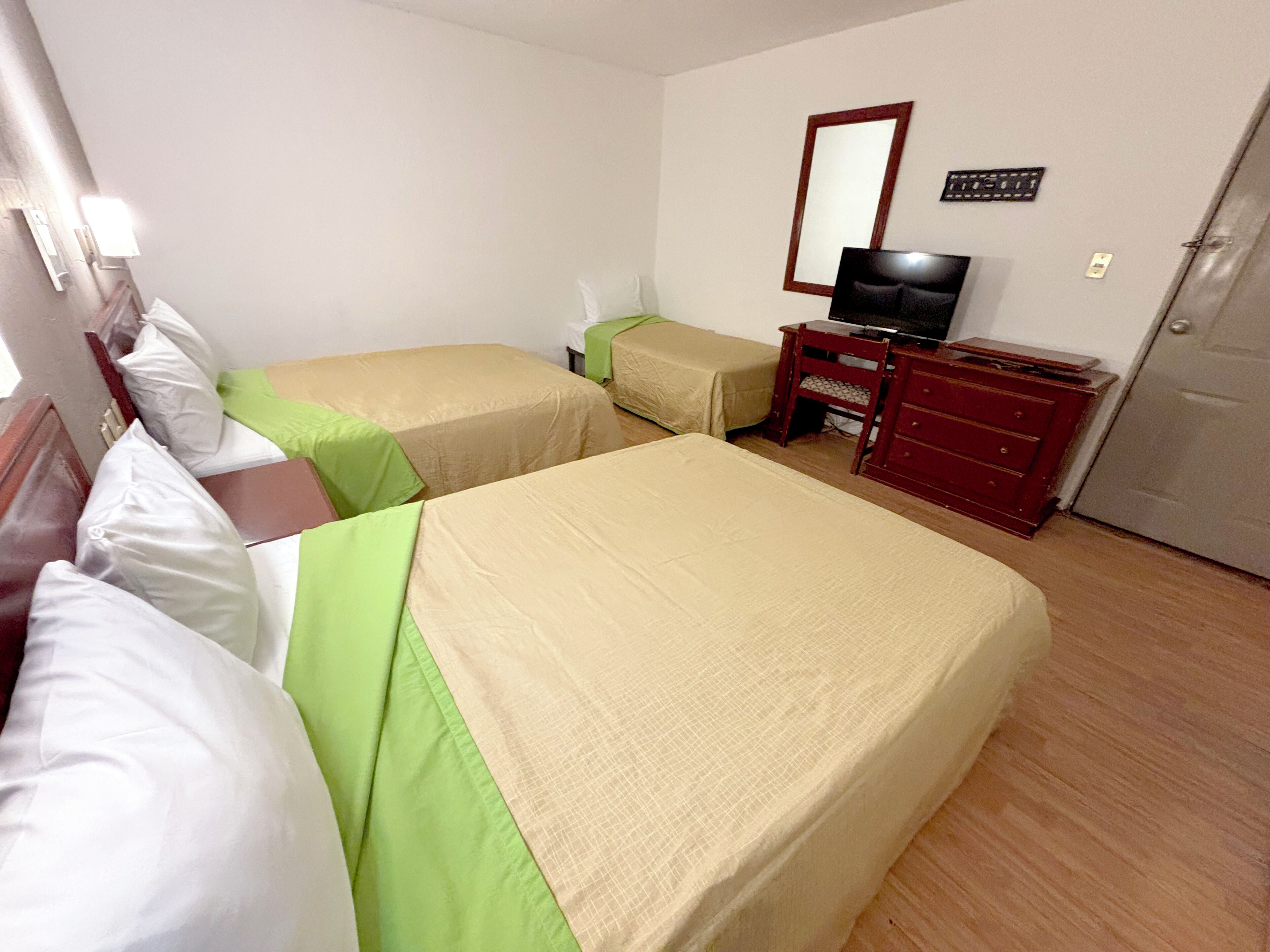 Una habitación de hotel con dos camas, televisión, cómoda y espejo.