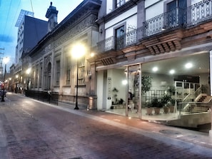 A hotel with a glass entrance, a staircase leading to the entrance, and a balcony with wrought iron railings. - Enterprise Inn Plaza (León)