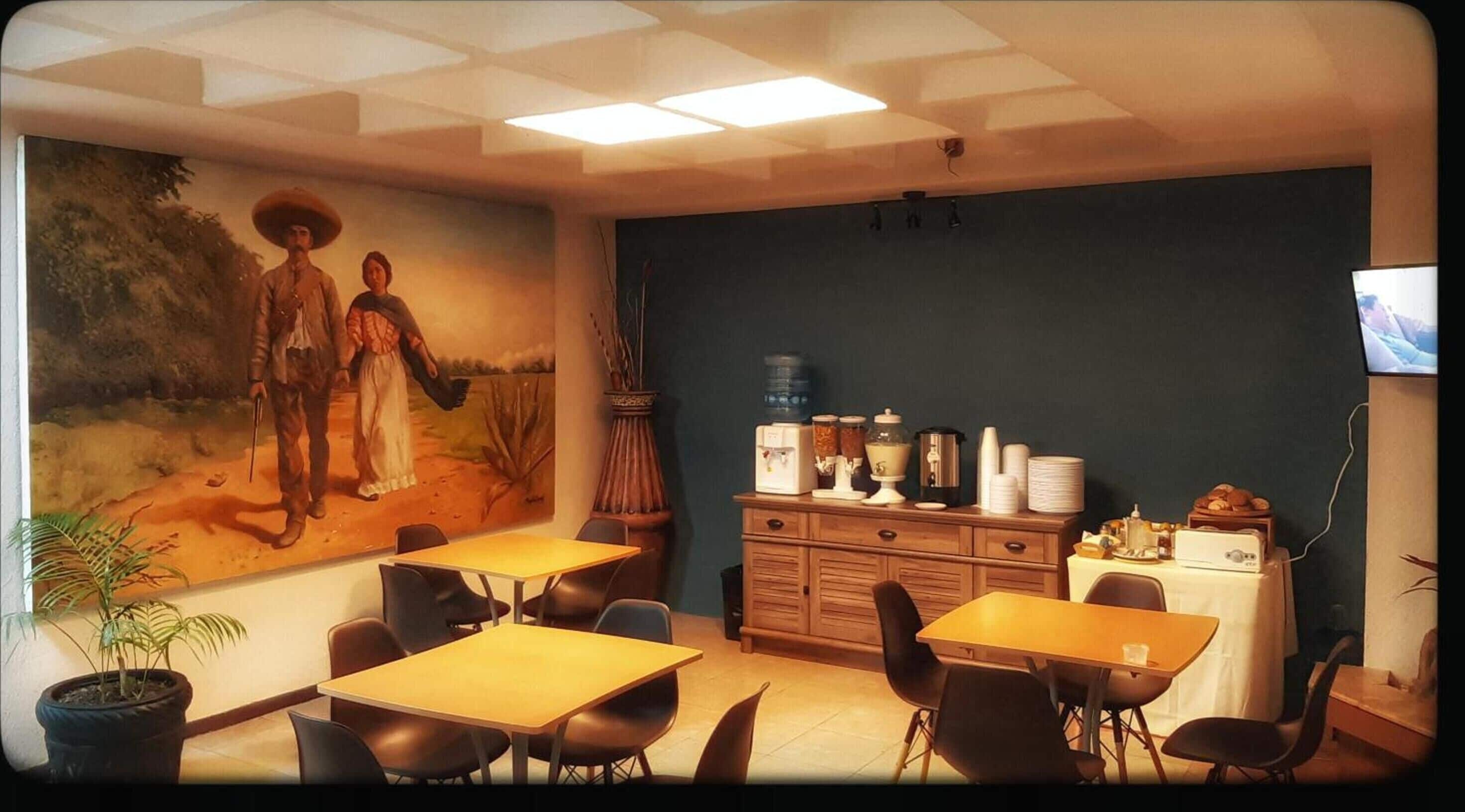 A dining area with tables, chairs, a mural, a water dispenser, and a television.