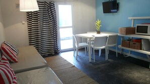 A room with a bed, a table with chairs, a TV, and a window with curtains. - Departamentos El Terrado II (Las Grutas)